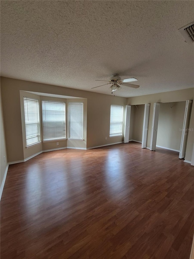 unfurnished room featuring a textured ceiling, ceiling fan, and dark hardwood / wood-style floors