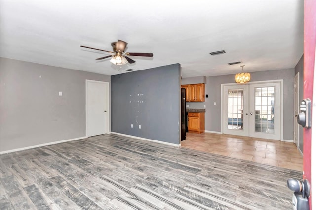 unfurnished living room featuring french doors, light hardwood / wood-style floors, and ceiling fan with notable chandelier