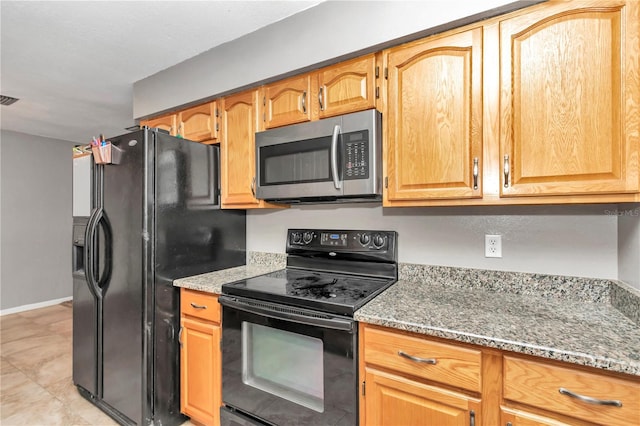 kitchen featuring light stone counters and black appliances