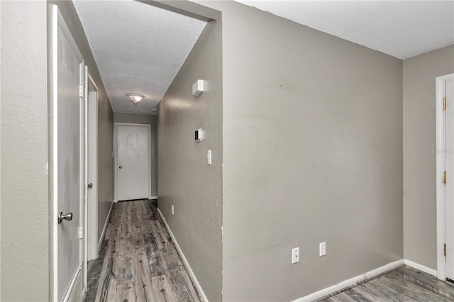 corridor with wood-type flooring and a textured ceiling