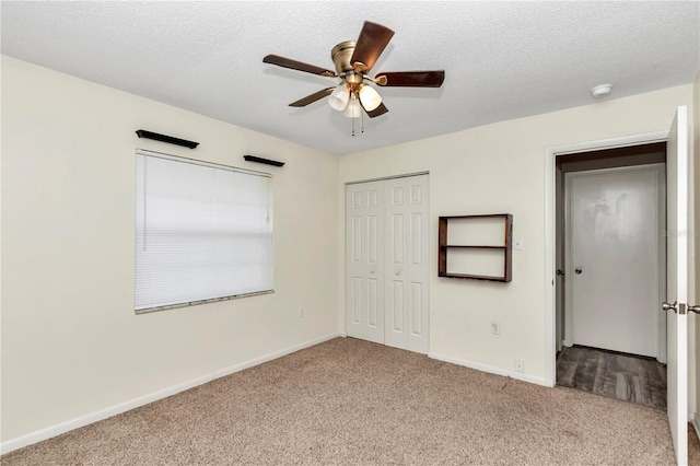 unfurnished bedroom featuring light carpet, a textured ceiling, a closet, and ceiling fan