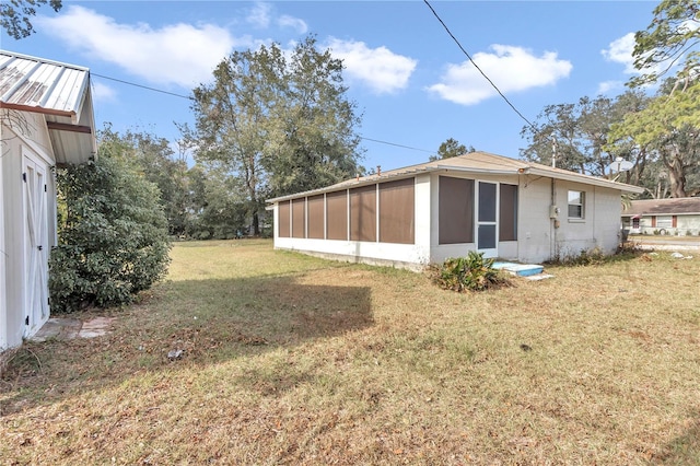 view of side of property featuring a sunroom and a lawn