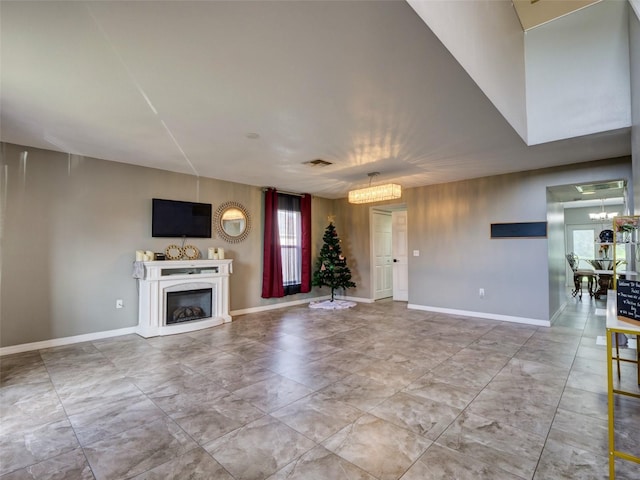 unfurnished living room featuring a premium fireplace and an inviting chandelier