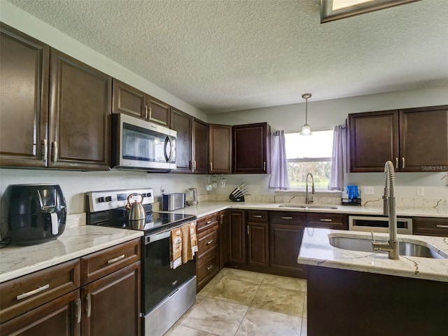 kitchen with pendant lighting, dark brown cabinets, sink, and appliances with stainless steel finishes