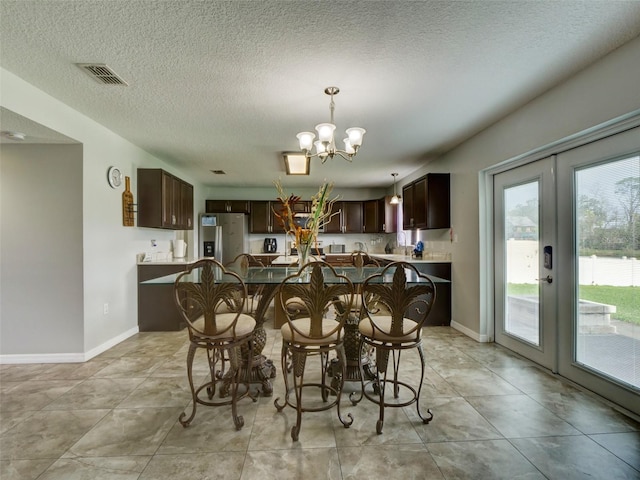 dining room with french doors, a chandelier, and a textured ceiling