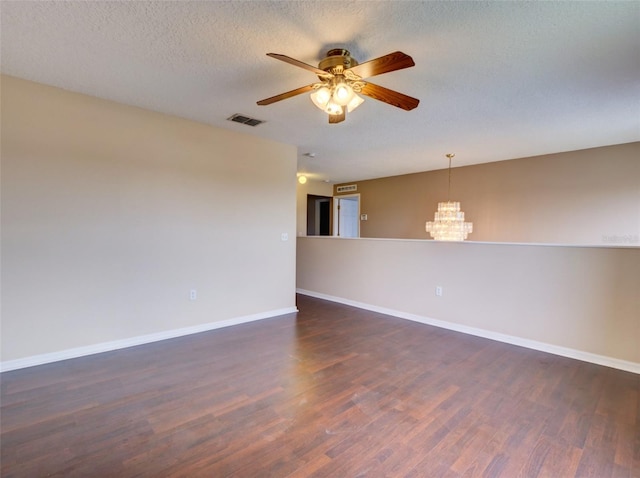 empty room with ceiling fan with notable chandelier, a textured ceiling, and dark wood-type flooring