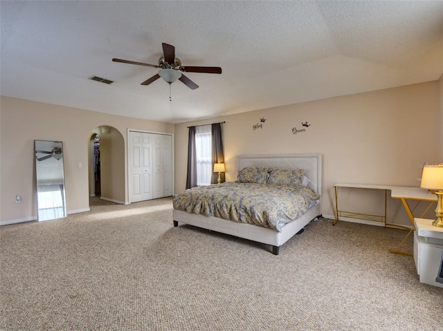 carpeted bedroom featuring a textured ceiling, a closet, and ceiling fan