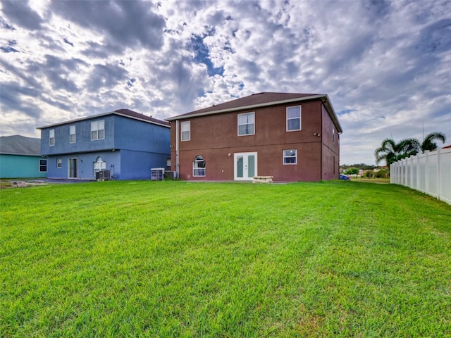 rear view of house featuring french doors, cooling unit, and a lawn