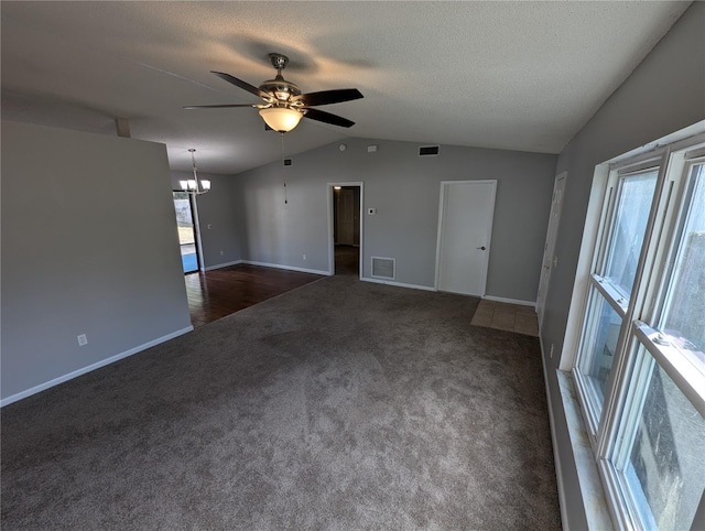 spare room featuring a textured ceiling, ceiling fan with notable chandelier, dark carpet, and lofted ceiling