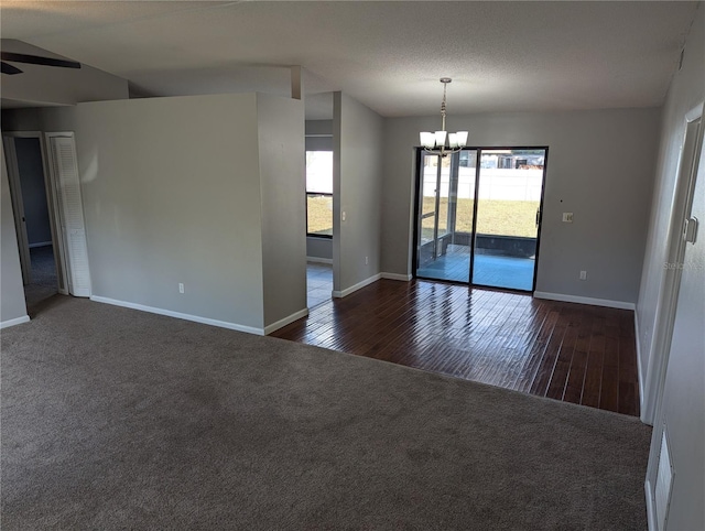 carpeted empty room with vaulted ceiling and ceiling fan with notable chandelier