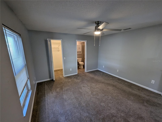 unfurnished bedroom with a walk in closet, ceiling fan, a textured ceiling, connected bathroom, and a closet