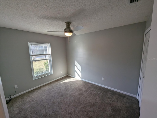 unfurnished room with ceiling fan, a textured ceiling, and dark colored carpet