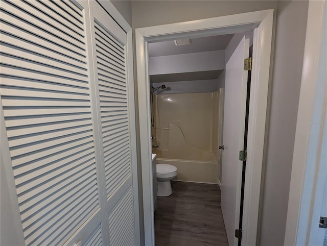 bathroom with wood-type flooring, bathing tub / shower combination, and toilet