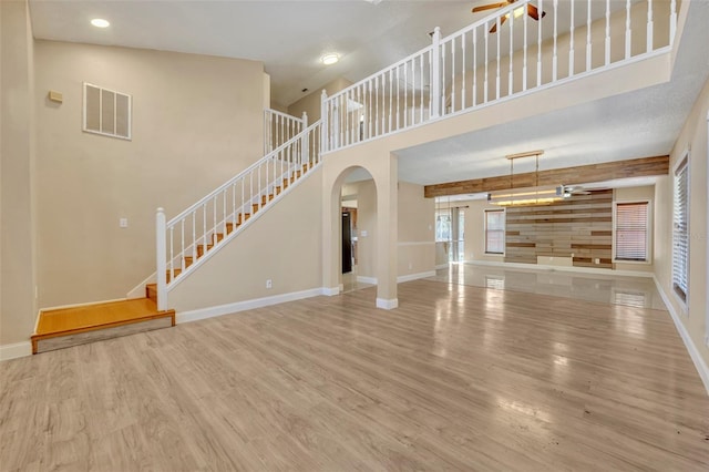 unfurnished living room featuring hardwood / wood-style floors, a towering ceiling, and ceiling fan