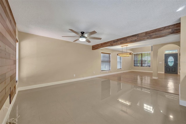 tiled empty room featuring beamed ceiling, a textured ceiling, and ceiling fan