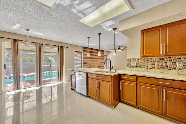 kitchen featuring ceiling fan, sink, stainless steel dishwasher, a textured ceiling, and decorative light fixtures