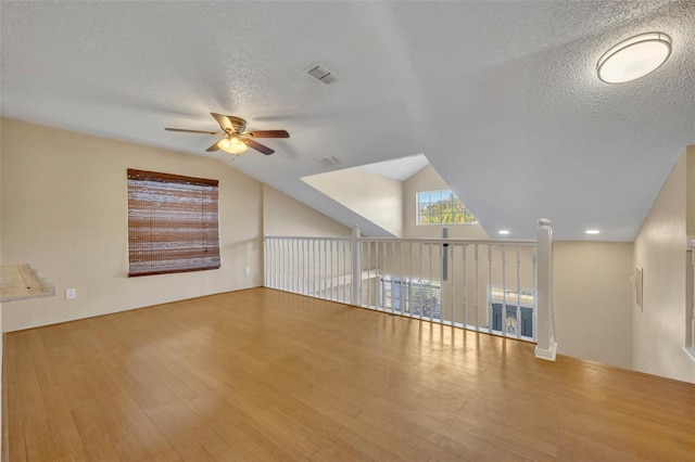 interior space with a textured ceiling, hardwood / wood-style flooring, vaulted ceiling, and ceiling fan