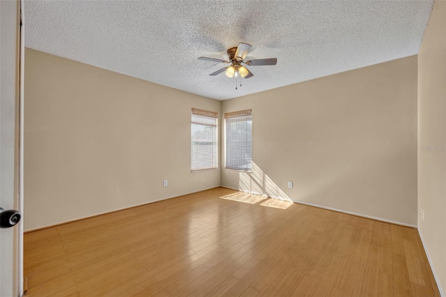 spare room featuring ceiling fan, light wood-type flooring, and a textured ceiling