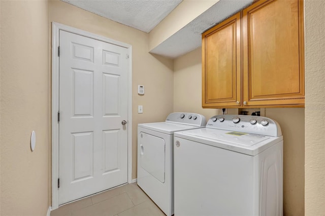 laundry room featuring washer and clothes dryer, cabinets, light tile patterned floors, and a textured ceiling