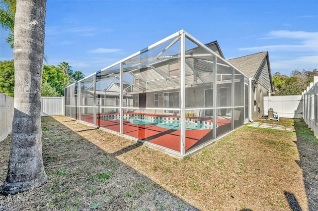 back of property with a fenced in pool and glass enclosure