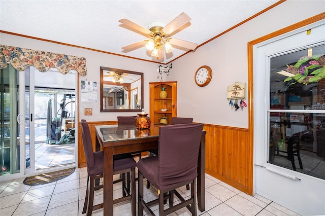 tiled dining area with wooden walls, ceiling fan, a textured ceiling, and ornamental molding