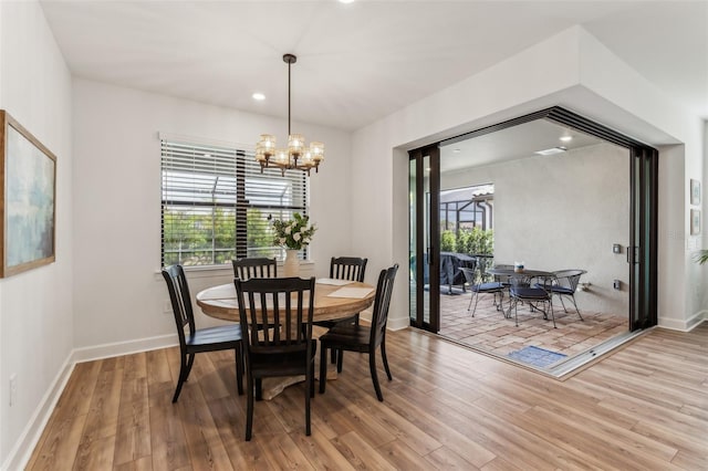 dining space with light hardwood / wood-style flooring, plenty of natural light, and a notable chandelier