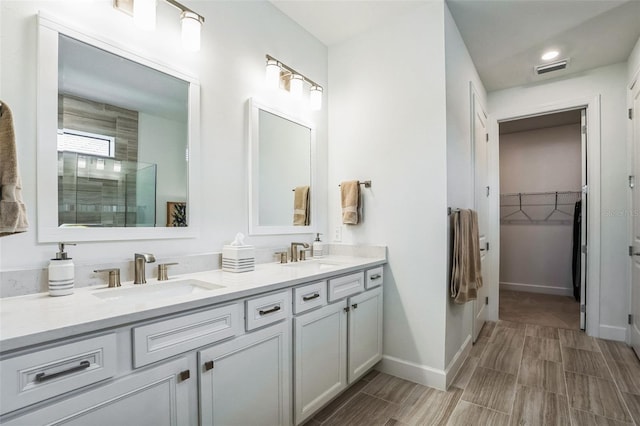 bathroom with a tile shower and vanity