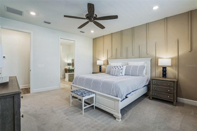 bedroom with ceiling fan, light colored carpet, and connected bathroom