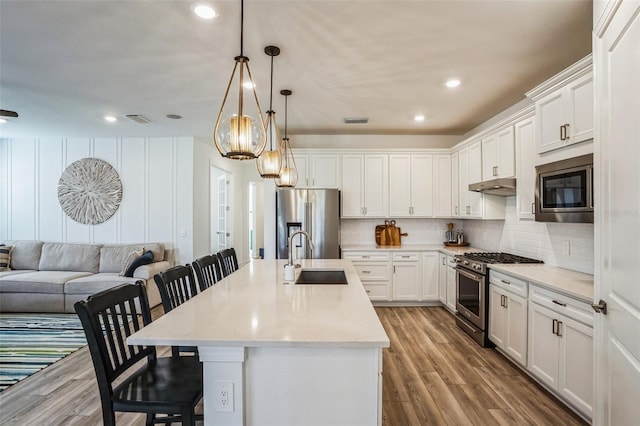 kitchen featuring appliances with stainless steel finishes, a center island with sink, a breakfast bar area, and sink