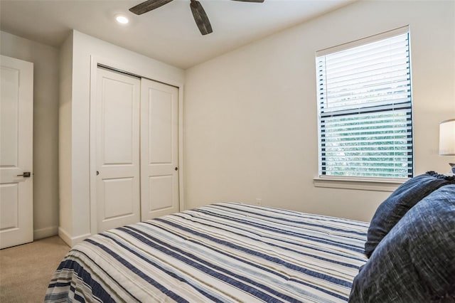 bedroom with multiple windows, light colored carpet, a closet, and ceiling fan