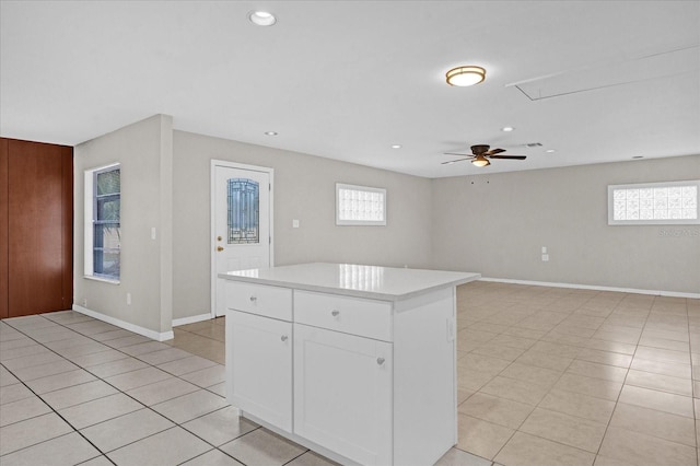 kitchen featuring white cabinets, a center island, light tile patterned floors, and a wealth of natural light