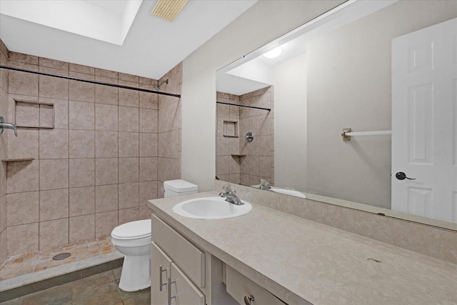 bathroom featuring a tile shower, vanity, a skylight, and toilet