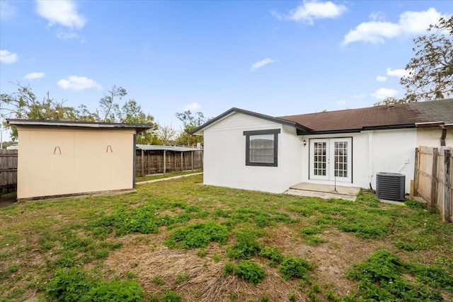 back of property with a lawn, central air condition unit, and french doors