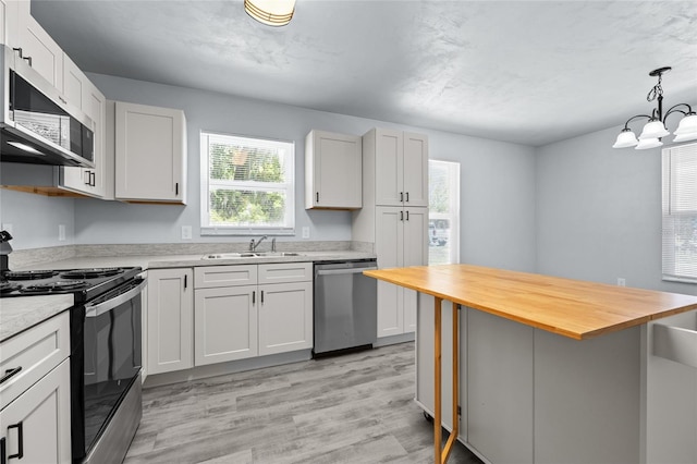 kitchen with white cabinets, sink, stainless steel appliances, and an inviting chandelier