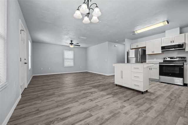 kitchen with white cabinets, pendant lighting, light wood-type flooring, and appliances with stainless steel finishes