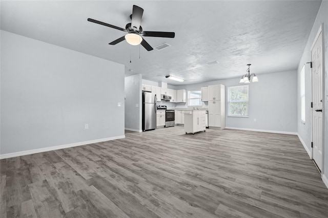 unfurnished living room with a textured ceiling, ceiling fan with notable chandelier, and hardwood / wood-style flooring