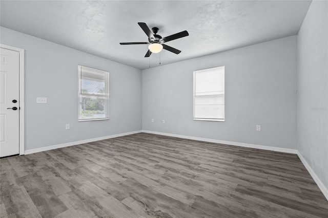 empty room with hardwood / wood-style flooring, ceiling fan, and a healthy amount of sunlight