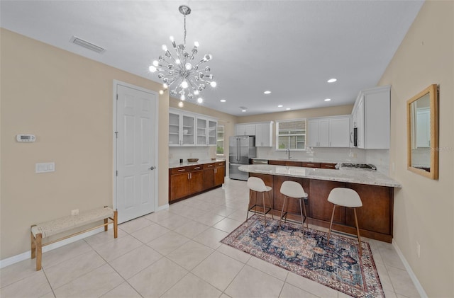 kitchen with white cabinets, appliances with stainless steel finishes, decorative light fixtures, a kitchen bar, and a chandelier