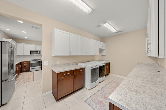 clothes washing area featuring washer / dryer, a textured ceiling, and light tile patterned flooring