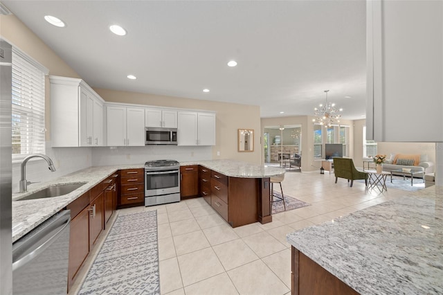 kitchen with sink, a chandelier, a kitchen bar, white cabinets, and appliances with stainless steel finishes