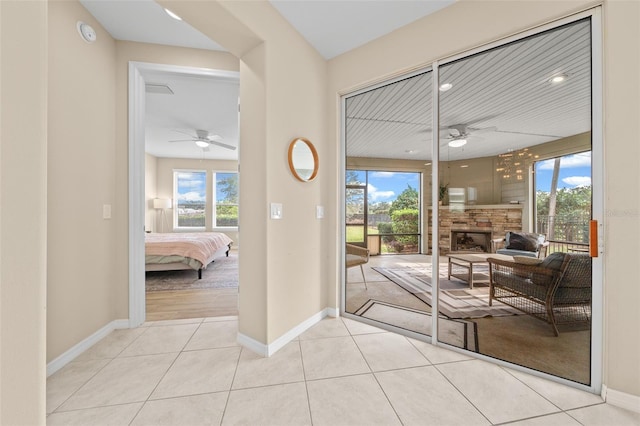 entryway featuring ceiling fan, a fireplace, and light tile patterned floors