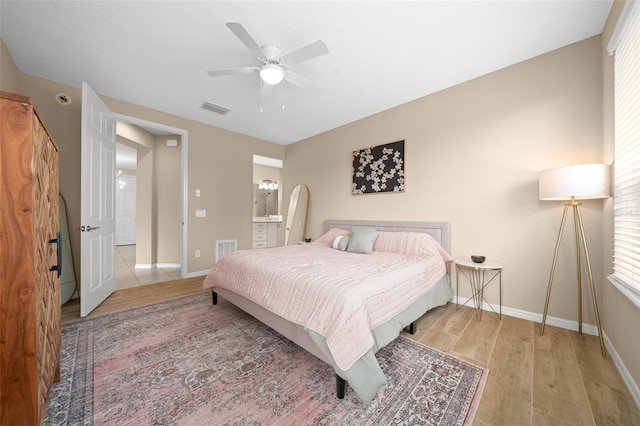 bedroom featuring ceiling fan, ensuite bath, and light hardwood / wood-style flooring