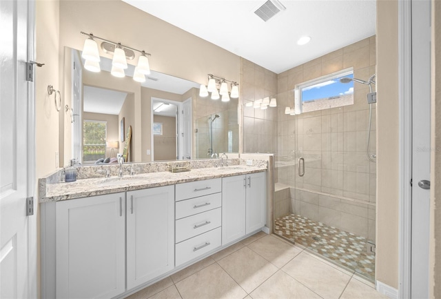 bathroom with tile patterned floors, vanity, a healthy amount of sunlight, and a shower with shower door