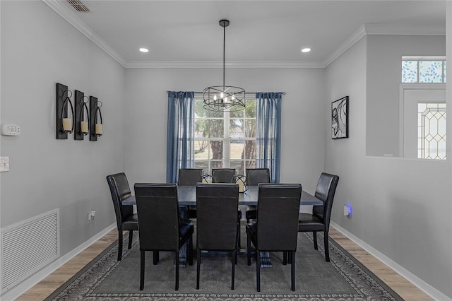 dining space with a chandelier, hardwood / wood-style floors, and ornamental molding