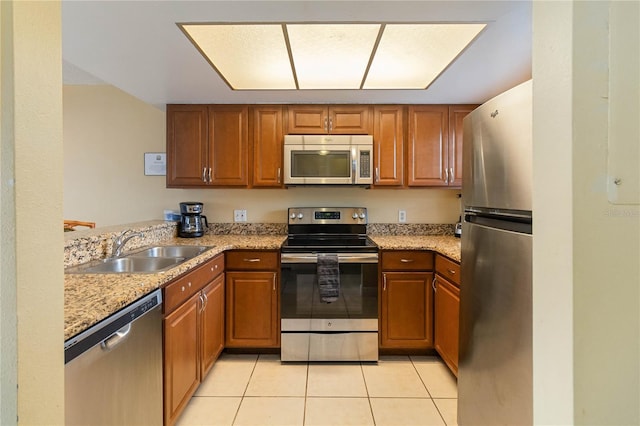2007 Disney Mgm Studio Ct, Kissimmee, FL 34746 - kitchen with stainless steel appliances, brown cabinetry, light tile patterned flooring, and light stone countertops
