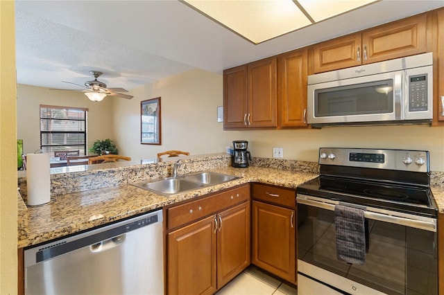 2007 Disney Mgm Studio Ct, Kissimmee, FL 34746 - kitchen with appliances with stainless steel finishes, brown cabinetry, a peninsula, and light stone counters
