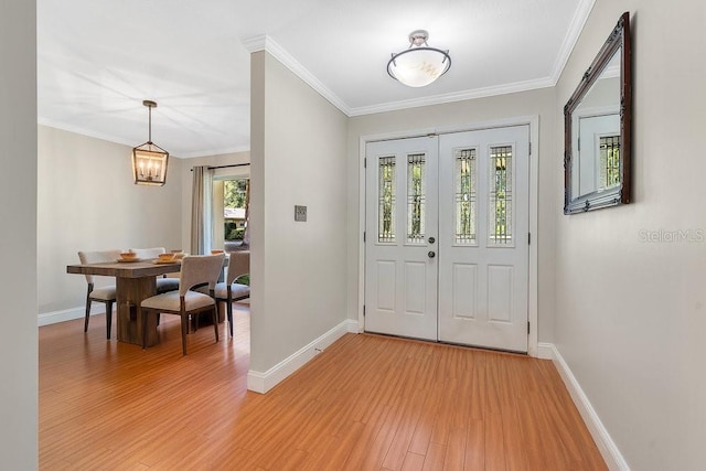 foyer entrance featuring ornamental molding, light wood-type flooring, and baseboards