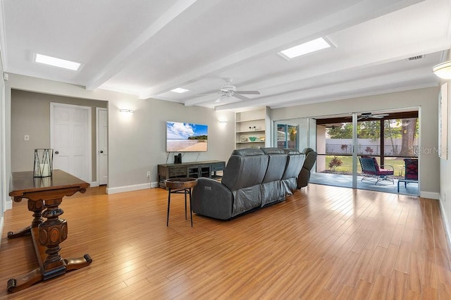 living room with light wood-type flooring, baseboards, and beamed ceiling