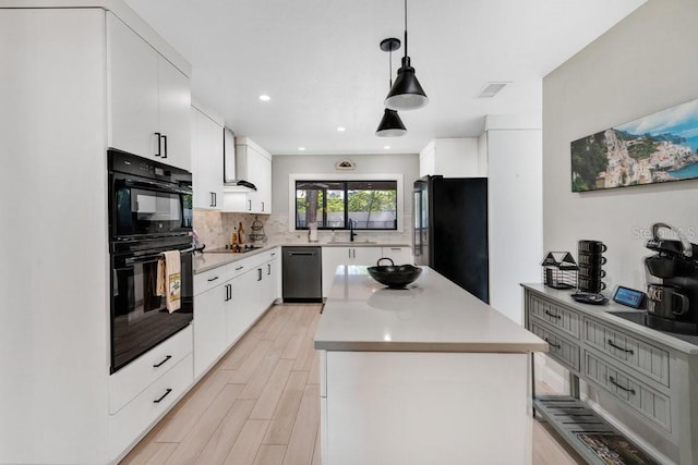 kitchen featuring a sink, a kitchen island, visible vents, backsplash, and black appliances