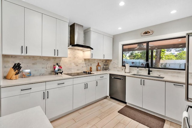 kitchen with dishwasher, wall chimney exhaust hood, black electric stovetop, light countertops, and a sink